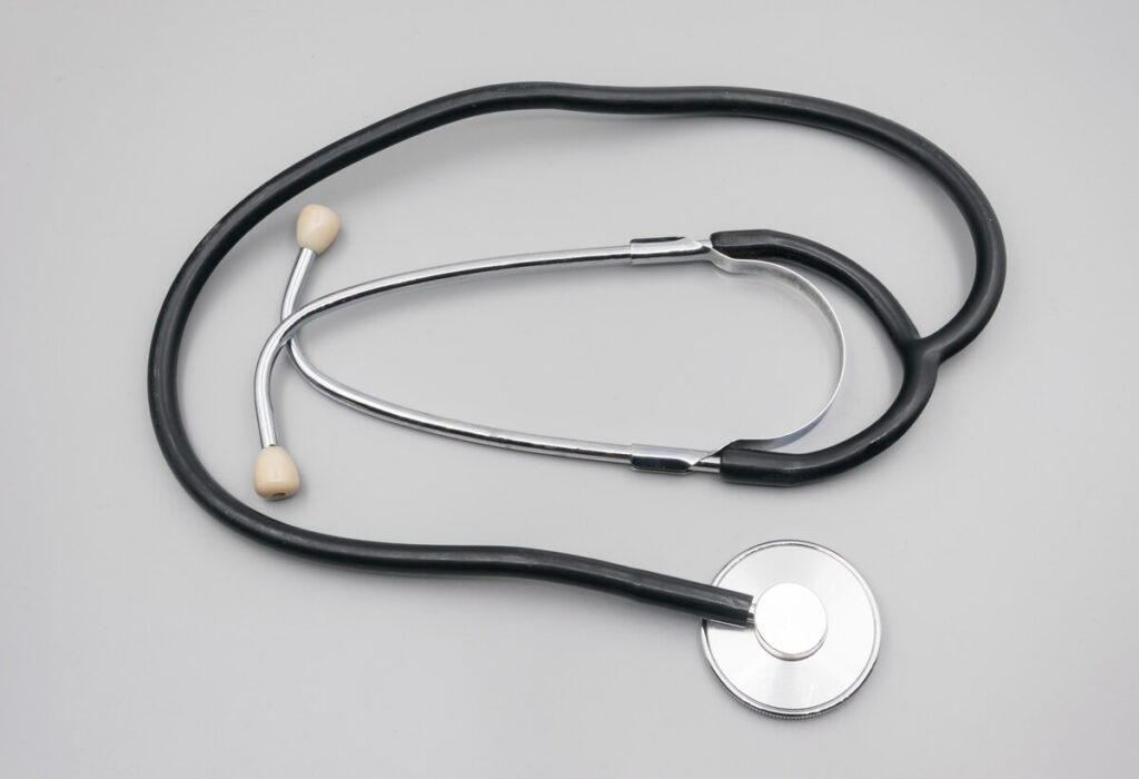 A black and silver stethoscope on a pale background.